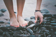 Image of a person picking up a stone barefeet